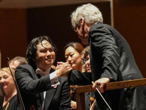 Pinchas Zukerman and NACO concertmaster Yosuke Kawasaki exchange a handshake at the end of the concert in Bristol, England.