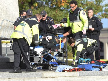 Police and paramedics tend to a soldier shot at the National Memorial near Parliament Hill in Ottawa on Wednesday Oct.22, 2014. Police are expanding a perimeter around Parliament Hill after a gunman opened fire at the National War Memorial, wounding a soldier, then moved to nearby Parliament Hill where he was reportedly shot by Parliament's sergeant-at-arms after wounding a security guard.