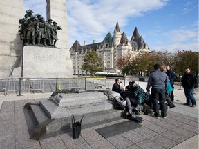 Police, bystanders and soldiers aid a fallen soldier at the War Memorial as police respond to an apparent terrorist attack in Ottawa.