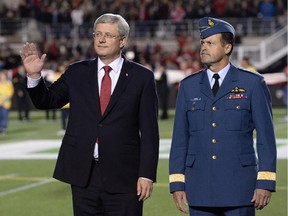Prime Minister Stephen Harper, left, and General Thomas Lawson, Chief of the Defence Staff, participate in a tribute to the Canadian Forces, as well as fallen heroes, Corporal Nathan Cirillo and Warrant Officer Patrice Vincent, before the start of CFL action between the Ottawa Redblacks and the Montreal Alouettes in Ottawa on Friday Oct. 24, 2014.