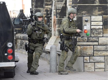 RCMP intervention team members walk past a gate on Parliament hill in Ottawa Wednesday Oct.22, 2014. A Canadian soldier standing guard at the National War Memorial in Ottawa has been shot by an unknown gunman and there are reports of gunfire inside the halls of Parliament.
