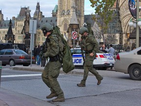 RCMP tactical officers cross the road heading towards the Langevin Block as police respond to an attack in Ottawa on Oct. 22, 2014.