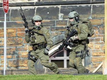 An RCMP intervention team run next to a Parliament building in Ottawa Wednesday Oct.22, 2014. A Canadian soldier standing guard at the National War Memorial in Ottawa has been shot by an unknown gunman and there are reports of gunfire inside the halls of Parliament.