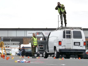 Quebec provincial police investigators take photos at the scene where two soldiers were struck by a car in St-Jean-sur-Richelieu, Que. on  Monday.