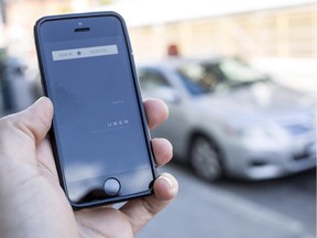 The UBER app on a smartphone is photographed with taxis in the background on Dalhousie Street in Ottawa in September.