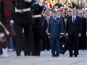 Chief of Defence Staff Tom Lawson, seen here with Prime Minister Stephen Harper, has cautioned members of the military about wearing their uniforms when not on duty, due to security concerns.