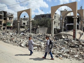 Palestinian girls walk past the rubble of a building which was destroyed during the Israeli army summer's military offensive on the Gaza Strip, on October 2, 2014. Israeli Prime Minister Benjamin Netanyahu has complained to UN chief Ban Ki-moon that a probe by the world body into the Gaza war is one-sided, his foreign ministry said.