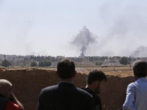 Turkish Kurds, standing in Mursitpinar, on the outskirts of Suruc, on the Turkey-Syria border, watch over the border the intensified fighting between militants of the Islamic State group and Kurdish forces in Kobani, Syria, Wednesday, Oct. 8, 2014. Kobani, also known as Ayn Arab and its surrounding areas have been under attack since mid-September, with militants capturing dozens of nearby Kurdish villages.