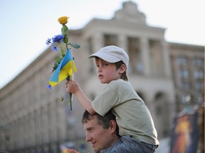 A young boy holds a flower and a Ukrainian flag as a 'flash mob' sing traditional Ukrainian songs and pray for a peaceful election, in Maidan Square on May 24, 2014 in Kiev, Ukraine.