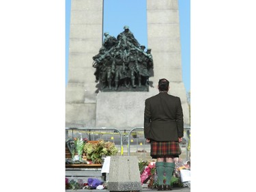 Veteran Ron Roach stands at attention after laying flowers in front of the War Memorial and Tomb of the Unknown Soldier.  Although much of the area around the National War Memorial and Parliament is still blocked off with police barriers, people were allowed to pay their respects Thursday, laying flowers and notes for the soldier killed in the terrorist attack Wednesday in Ottawa.