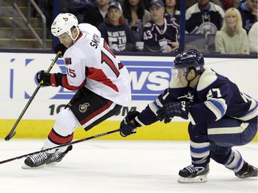 Ottawa Senators' Zack Smith, left, tries to control the puck as Columbus Blue Jackets' Ryan Murray defends during the first period.