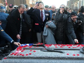 A veteran looks skyward and salutes after leaving his poppy at the Tomb of the Unknown Soldier following the official ceremony. Remembrance Day at the National War Memorial in Ottawa November 11, 2014.