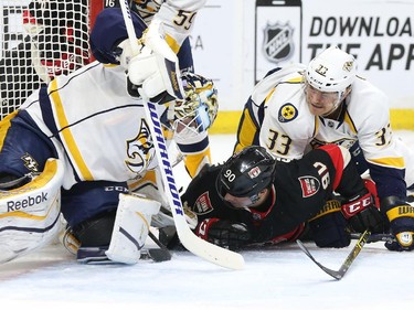 Alex Chiasson of the Ottawa Senators attacks the net of Carter Hutton as he is defended by #33 Colin Wilson of the Nashville Predators during first period NHL action.