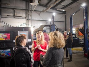 Amie Talbot, a local coloured pencil artist, talks to guests at Wicked Garage during Art on Wheels, an art show in a working automotive high-performance repair, customization and fabrication shop in Greely, Saturday, November 29, 2014.