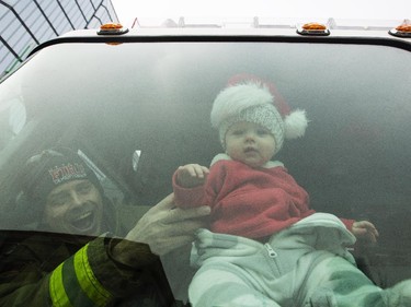 An infant gets a great view from the front window of an Ottawa fire truck during the 2014 Ottawa Professional Fire Fighters' Association's Help Santa Toy Parade in Ottawa Saturday