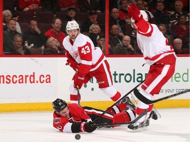Mark Stone #61 of the Ottawa Senators is tripped up by Darren Helm #43 and Jakub Kindl #4 of the Detroit Red Wings.
