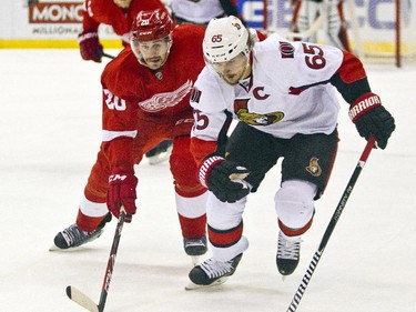 Detroit Red Wings forward Drew Miller (20) and Ottawa Senators defenseman Erik Karlsson (65), of Sweden, skate after the puck during the first period.