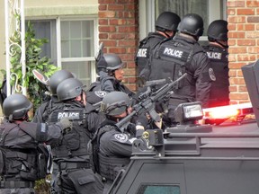 In this April 22, 2014, file phot, Nassau County police officers enter a home in Long Beach, N.Y., in search of an armed killer, based on a phone call that turned out to be a hoax. Authorities say the dangerous and costly prank known as 'swatting', is becoming increasingly popular among people who play combat games over live video feeds while thousands of people watch.