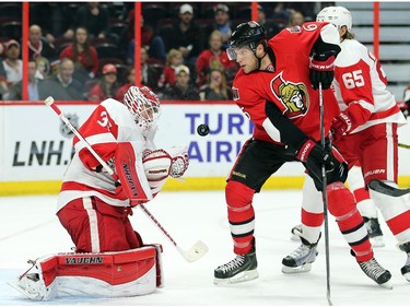 Goalie Jimmy Howard keeps his eye on the puck while Bobby Ryan moves closer in the first period.