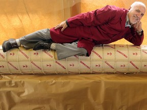 Joe Nicastro, co-owner of Nicastro Fine Foods, stretches out on Ottawa's biggest piece of cheese Monday at his Merivale Road store.