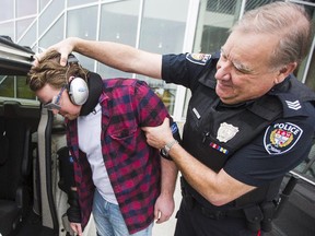 Ottawa Citizen reporter Drake Fenton, wearing an "impairment suit" aimed to give sober people the sensation of being drunk, gets put into a RIDE vehicle under the watchful eye of Ottawa Police Sgt. John Kiss at Algonquin College Thursday, November 26, 2014. (Darren Brown/Ottawa Citizen)