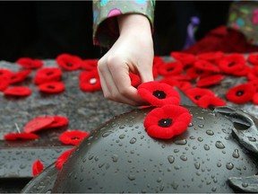 People place poppy pins at the National War Memorial: sales of the lapel pins are up this year.