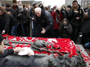 Members of the public place poppies on the Tomb of the Unknown Soldier following Remembrance Day ceremonies at the National War Memorial in Ottawa, on November 11, 2011.