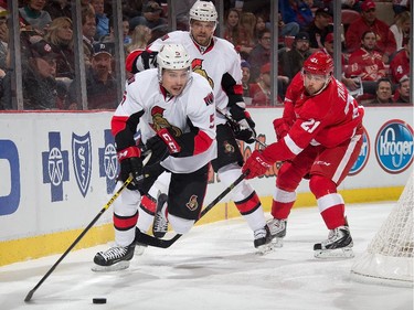 Cody Ceci #5 of the Ottawa Senators controls the puck in front of teammate Milan Michalek #9 and Tomas Tatar #21 of the Detroit Red Wings.
