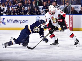 Jaden Schwartz #17 of the St. Louis Blues falls to the ice as Eric Gryba #62 of the Ottawa Senators skates on November 25, 2014 at Scottrade Center in St. Louis, Missouri.