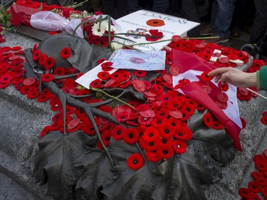 People place poppies at the Tomb of the Unknown Soldier following the Remembrance Day ceremony at the National War Memorial in Ottawa on Tuesday, Nov. 11, 2014.