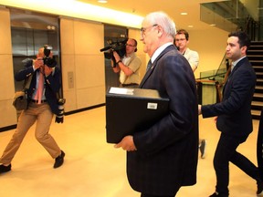 Veterans Affairs Minister Julian Fantino walks away from an angry milirary wife (not shown) after a Commons veterans committee in Ottawa in November 2014.
