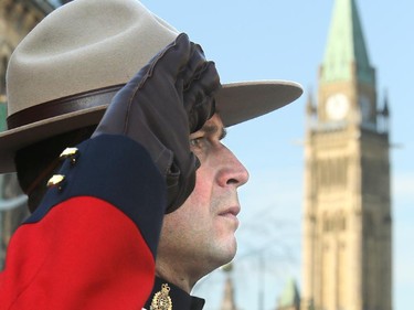 With Parliament Hill in the background, an RCMP mountie salutes the veterans. Remembrance Day at the National War Memorial in Ottawa