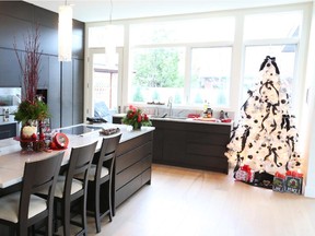 A tree decorated with black ribbons and feathers is visible from all corners of the open-plan living area. Red arrangements on the island and countertop add punch to the neutral decor.