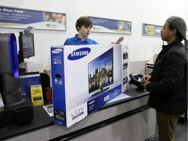 A cashier offers a protection plan as he processes a TV purchase on Boxing Day at the Best Buy on Merivale Road, Dec. 26, 2014.