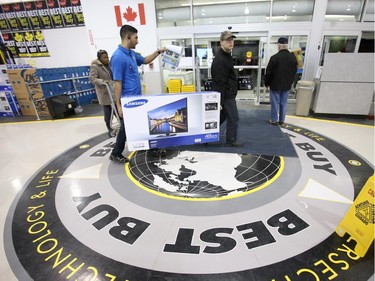 A clerk helps a customer carry a large-screen TV towards the checkout at Best Buy on Merivale Road on Boxing Day, Dec. 26, 2014.