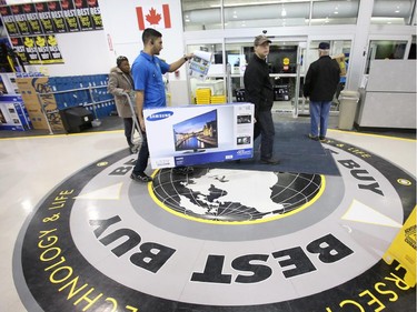A clerk helps a customer carry a large-screen TV to the checkout at Best Buy on Merivale Road on Boxing Day, Dec. 26, 2014.