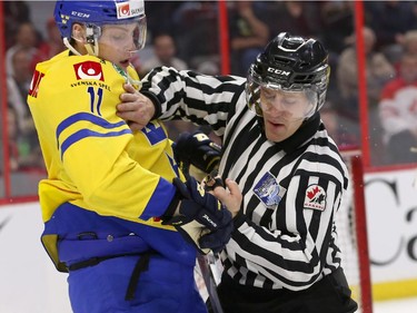 A linesman pushes Anton Biidn #11 of Team Sweden away from Frederik Gauthier #22 ofTeam Canada after pushing him to the ice in the third perioda during an World Junior Hockey pre-tournament game at Canadian Tire Centre in Ottawa on December 21, 2014.