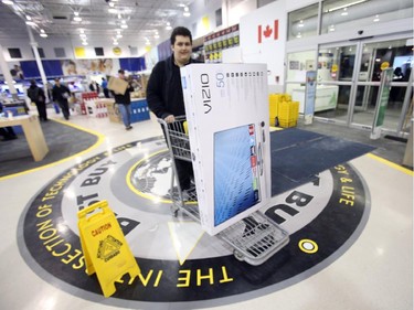 A man carts a large-screen TV towards the checkout at Best Buy on Merivale Road on Boxing Day, Dec. 26, 2014.