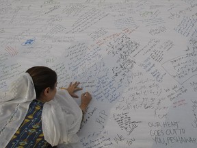 A Pakistani girl writes a message for students killed in a Dec. 16 Taliban attack on a military-run school, in Peshawar, Pakistan, Wednesday, Dec. 24, 2014.