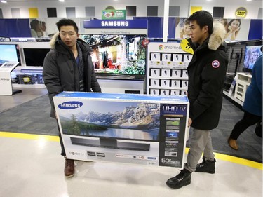 Albert Wong gets some help carrying a 50" TV from friend Kevin Yee  inside the Best Buy on Merivale Road, Dec. 26, 2014.