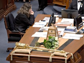 National Assembly employee Arianne Mignolet, left, sits at her desk during a ceremony to commemorate the 25th anniversary of the Polytechnique tragedy, Thursday, December 4, 2014 at the legislature in Quebec City. Fourteen white roses are sitting at the main desk, in memory of the 14 women who died in the tragedy.