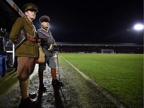 People in military WWI uniforms watch the "Game of Truce", a recreation of a First World War Christmas truce football match, in Aldershot, west of London, on December 17, 2014. The match marks the 100th anniversary of a truce that took hold on Christmas Eve and Christmas Day 1914, in which enemy British and German troops emerged from their trenches along the Western Front to talk, joke, share cigarettes and kick a ball about in no-man's-land.