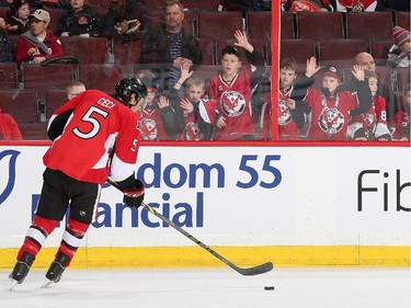 Minor hockey kids try to get the attention of Cody Ceci #5 of the Ottawa Senators as he skates by during warmups prior to the NHL game against the Buffalo Sabres.