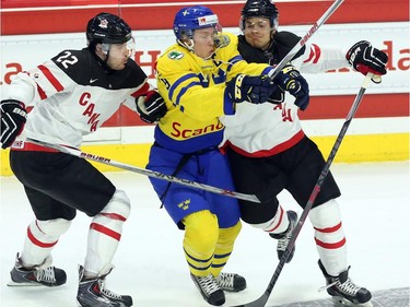 Team Sweden's Jacob de la Rosa (9) is checked by Team Canada's Frederick Gauthier (2) and Madison Bowey (4) during first period exhibition hockey action in preparation for the upcoming IIHF World Junior Championships in Ottawa Sunday, December 21, 2014.