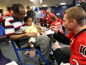 Chris Neil of the Ottawa Senators signs an autograph for  Tayework Taye and Rafel, 2 years 10 months during his team's visit at CHEO, December 10, 2014.