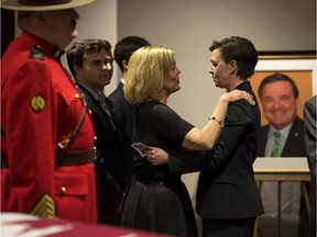 Ontario MPP Christine Elliott, left, hugs MP Kelly Leitch in front of the casket of her husband, the late former federal finance minister Jim Flaherty, during visitation in Whitby, Ont., on Tuesday, April 15, 2014.