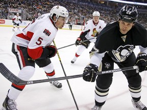 Pittsburgh Penguins' Craig Adams (27) prepares of absorb a hit by Ottawa Senators' Cody Ceci (5) during the second period of an NHL hockey game in Pittsburgh, Saturday, Dec. 6, 2014.