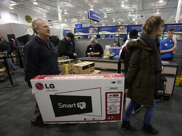 Customers carry a large-screen TV to the cashier at the Best Buy on Merivale Road on Boxing Day, Dec. 26, 2014.