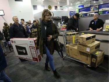 Customers carry a large-screen TV to the cashier at the Best Buy on Merivale Road on Boxing Day, Dec. 26, 2014.