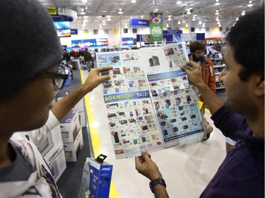 Customers check a flyer on at the Best Buy on Merivale Road on Boxing Day, Dec. 26, 2014.